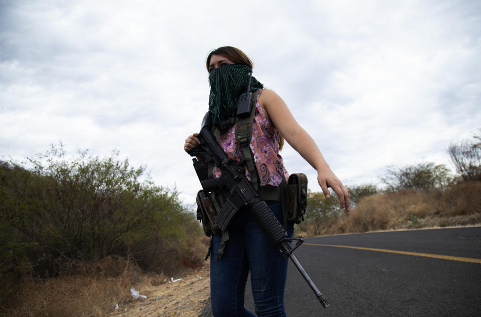 An armed woman who goes by the nickname "La Guera," and who says she is a member of a female-led, self-defense group, patrols the edge of her town El Terrero, where it shares a border with the town of Aguililla, in Michoacan state, Mexico, Thursday, Jan. 14, 2021. In other towns nearby, residents have dug trenches across roadways leading into neighboring Jalisco state, to keep attackers out. (AP Photo/Armando Solis)