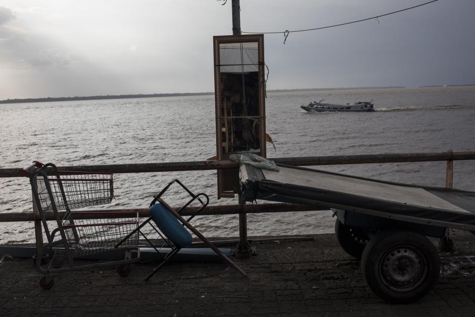 In this Aug. 31, 2019 photo, carts used by workers of the Ver-o-Peso riverside market sit idle as a public ferry crosses Guajara Bay in Belém, Brazil. Guajara Bay is formed by the confluence of the Para and Guama Rivers. (AP Photo/Rodrigo Abd)