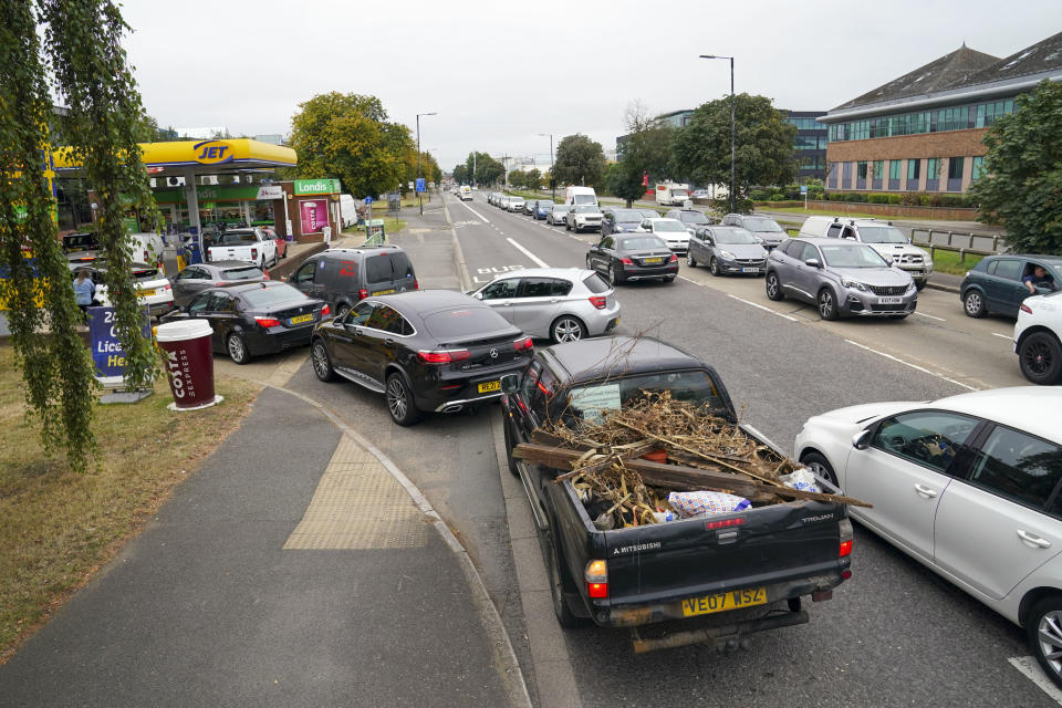 Cars queue outside a petrol station in Slough, England, Saturday Sept. 25, 2021. The haulage industry says the U.K. is short tens of thousands of truckers, due to a perfect storm of factors including the coronavirus pandemic, an aging workforce and an exodus of European Union workers following Britain’s departure from the bloc. BP and Esso shut a handful of their gas stations this week, and motorists have formed long lines as they try to fill up in case of further disruption. (Steve Parsons/PA via AP)