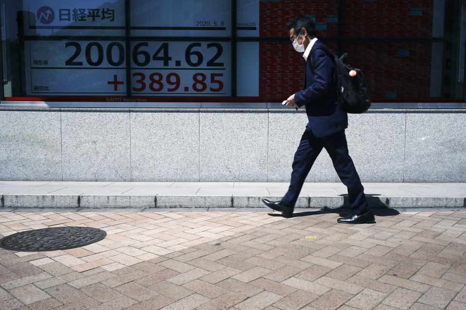 A man wearing a face mask to help curb the spread of the coronavirus walks past an electronic stock board showing Japan's Nikkei 225 index at a securities firm in Tokyo Friday, May 8, 2020. Asian shares surged Friday on optimism the worst of the economic fallout from the pandemic may be over, as Wall Street logged its biggest rally in a week.(AP Photo/Eugene Hoshiko)