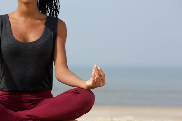 Close up portrait of a young woman in lotus position with yoga hands at the beach