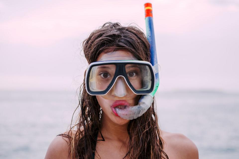 young woman with diving goggles and snorkel pulling funny faces