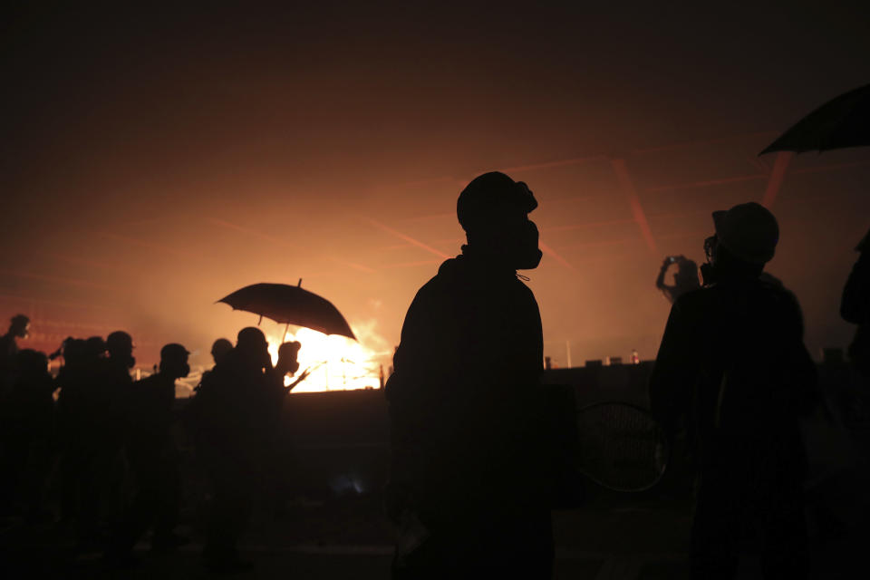 Protesters react outside of Hong Kong Polytechnic University as police storm the campus in Hong Kong, early Monday, Nov. 18, 2019. Fiery explosions were seen early Monday as Hong Kong police stormed into a university held by protesters after an all-night standoff. (AP Photo/Kin Cheung)