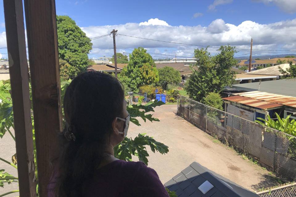 Susan Galicha looks out at a train on Honolulu's rail track in the distance from her front porch in Waipahu, Hawaii, on Oct. 30, 2020. Honolulu is building one of the nationís most expensive rail lines to address some of the nation's worst traffic but tax revenue declines during the pandemic and spiraling costs mean it doesn't currently have enough money to finish the 20-mile route as planned. (AP Photo/Audrey McAvoy)