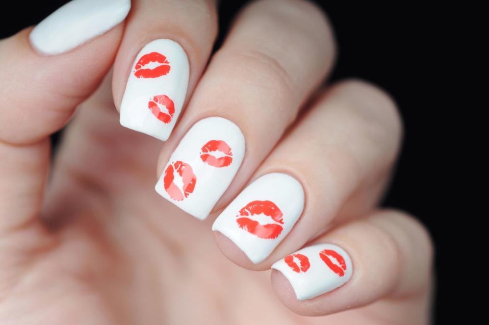 <p>This Valentine's Day, go with a flirty look! These nails pair bright white polish with sexy red lipstick kisses.</p>