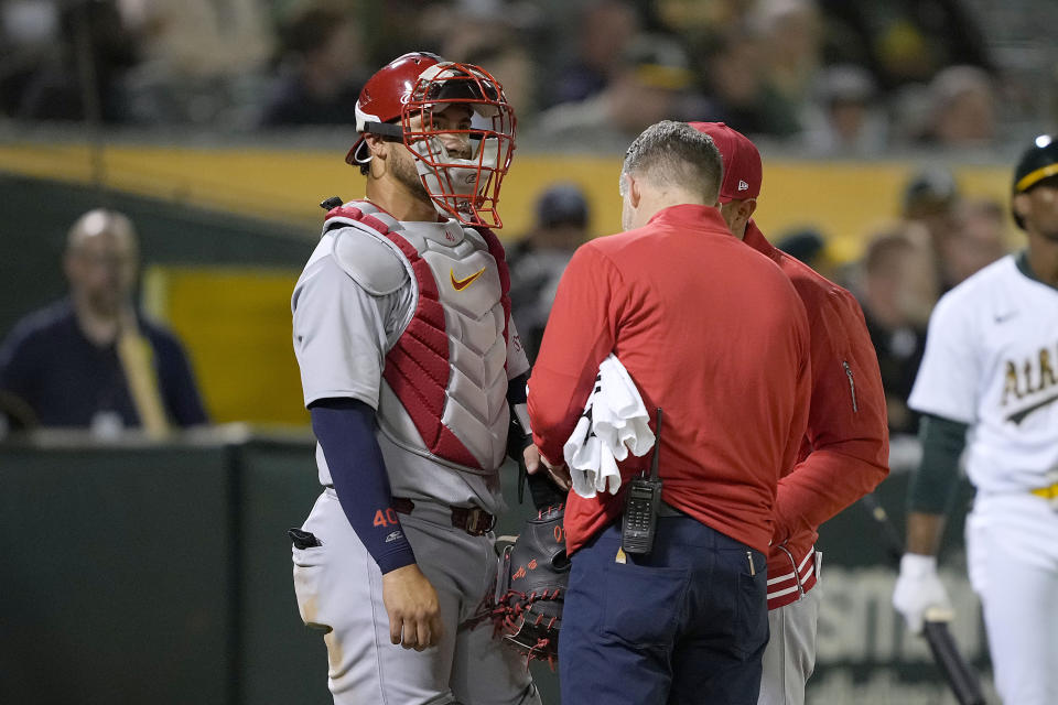 St. Louis Cardinals catcher Willson Contreras, left, is checked by a trainer during the eighth inning of the team's baseball game against the Oakland Athletics in Oakland, Calif., Tuesday, April 16, 2024. (AP Photo/Tony Avelar)
