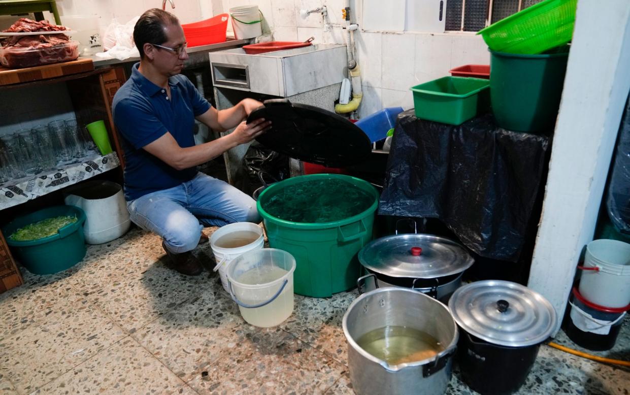 Restaurant owner Luis Alirio Soler fills buckets of water as restrictions hit business in Bogota