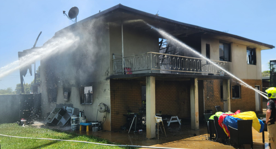 Firefighters extinguish a Wollongbar house fire. The gutted house is seen the roof caved in, windows smashed and blackened walls.