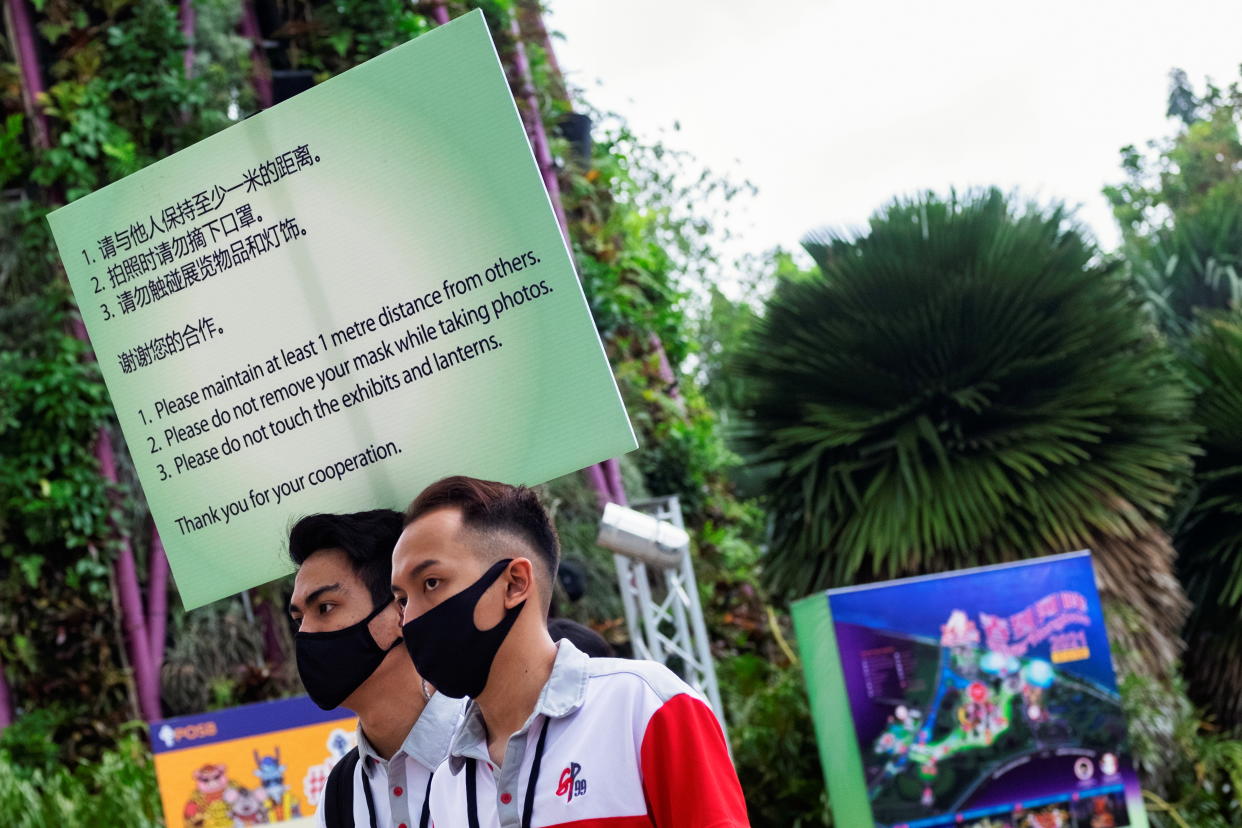 Event marshals carry a sign to remind visitors to comply with measures to curb the coronavirus disease (COVID-19) outbreak during the annual River Hongbao festival on the eve of the Chinese Lunar New Year of the Ox, otherwise known as the Spring Festival, at Singapore's Gardens by the Bay, February 11, 2021. REUTERS/Loriene Perera