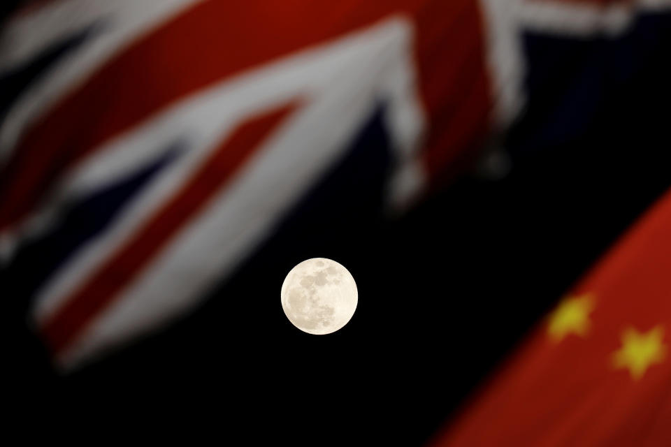 The moon is seen between British and Chinese flags raised at Tiananmen Square in Beijing as British Prime Minister Theresa May visited China's capital on Jan. 31, 2018.