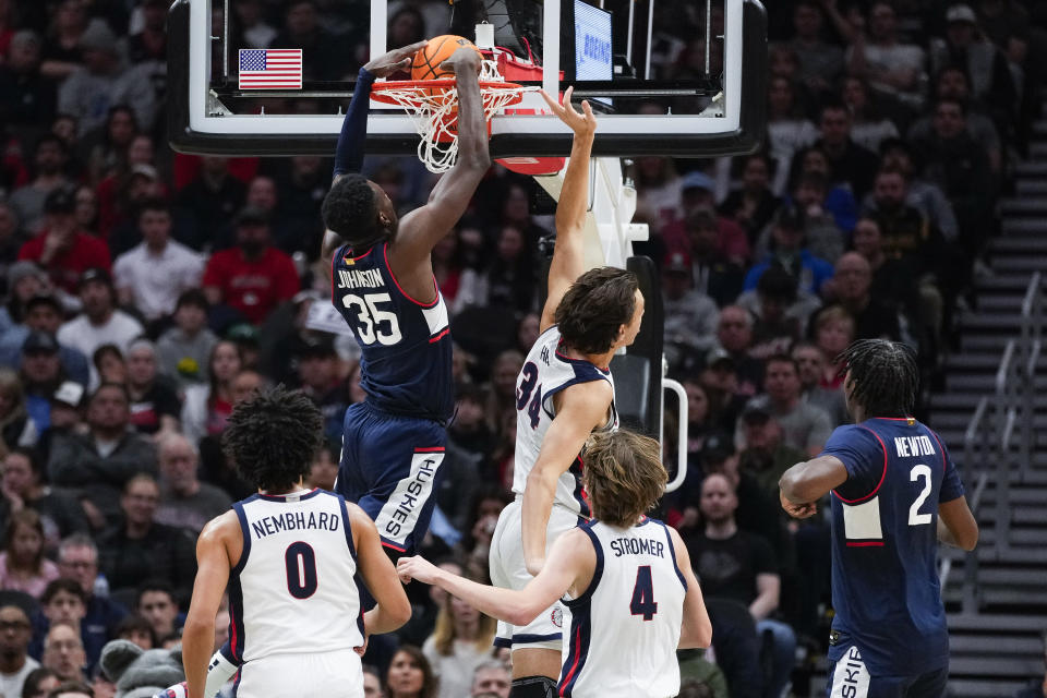 UConn forward Samson Johnson (35) dunks next to Gonzaga forward Braden Huff (34) as Ryan Nembhard (0) and Dusty Stromer (4) watch during the first half of an NCAA college basketball game Friday, Dec. 15, 2023, in Seattle. (AP Photo/Lindsey Wasson)