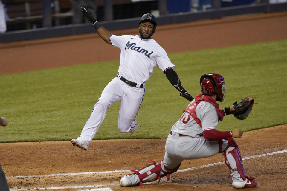 Miami Marlins' Starling Marte, left, scores on a double hit by Jesus Aguilar as Philadelphia Phillies catcher Rafael Marchan waits for the throw during the third inning of a baseball game, Monday, Sept. 14, 2020, in Miami. (AP Photo/Lynne Sladky)