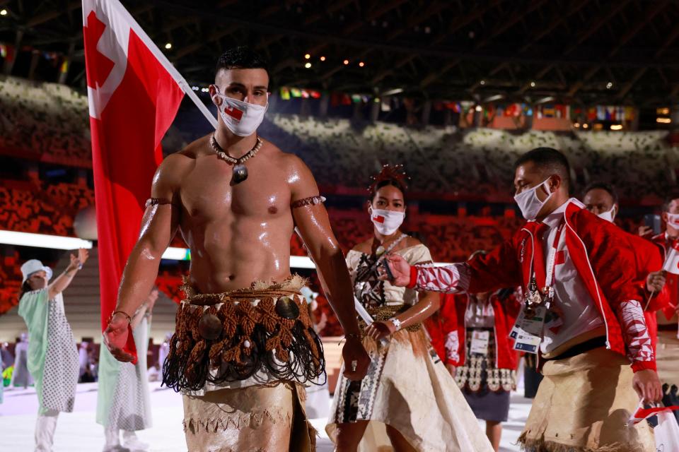 Tonga's flag bearers Pita Taufatofua (L) and Malia Paseka  (2L)  lead their delegation as they parade  during the opening ceremony of the Tokyo 2020 Olympic Games, at the Olympic Stadium, in Tokyo, on July 23, 2021. (Photo by Odd ANDERSEN / AFP) (Photo by ODD ANDERSEN/AFP via Getty Images)