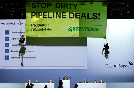 Chairman Urs Rohner and CEO Tidjane Thiam of Swiss bank Credit Suisse look up as activists of environmental group Greenpeace unveil a banner to protest against the financing of the Dakota-Access oil pipeline during the bank's annual shareholder meeting in Zurich, Switzerland April 28, 2017. REUTERS/Arnd Wiegmann