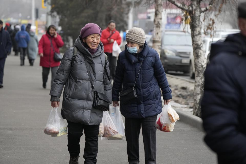 Two local women talk to each other as they walk through a street in Almaty, Kazakhstan, Tuesday, Jan. 11, 2022. Nearly 8,000 people in Kazakhstan were detained by police during protests that descended into violence last week and marked the worst unrest the former Soviet nation has faced since gaining independence 30 years ago, authorities said Monday. (AP Photo)