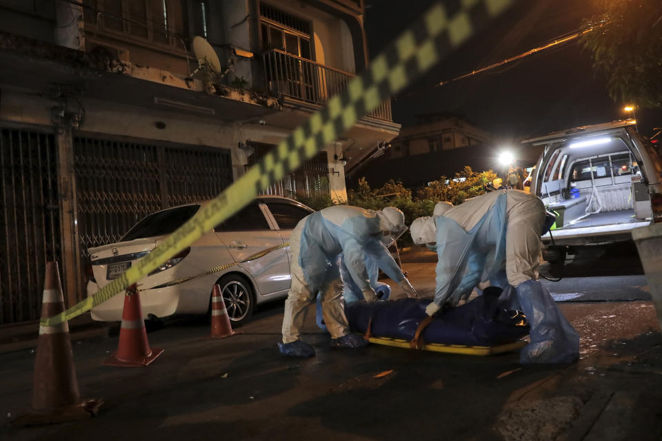 Thai volunteers with PPE protection suits collect a dead body which was left for hours on a road in Bangkok, Thailand on July 20, 2021. Thailand's already locked down capital on Friday, July 23, 2021 shut down parks and the few remaining public places available to residents, as the country registered a new record high of confirmed COVID-19 infections. The near total restriction on movements in the capital came as the prime minister demanded officials find ways to get the sick into hospitals after people were found dead on the streets of Bangkok. (Patipat Janthong/Voice via AP)