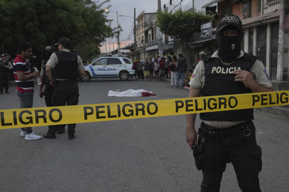 FILE - Police guard a crime scene where the body of a man, killed in unknown circumstances, lies covered on a street in Duran, Ecuador, Friday, July 21, 2023. The human toll of Ecuador’s transformation into a major drug trafficking hub has been immense, reflected in the country’s highest recorded annual number of violent deaths in 2022, at 4,600, double the previous year. (AP Photo/Dolores Ochoa, File)