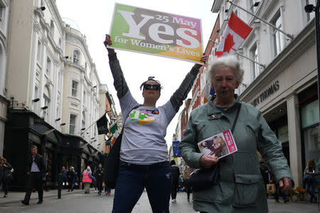 A woman holding a 'Vote No' leaflet walks past a pro-choice volunteer holding up a 'Yes' campaign poster on the street ahead of a 25th May referendum on abortion law, in Dublin, Ireland May 22, 2018. REUTERS/Clodagh Kilcoyne