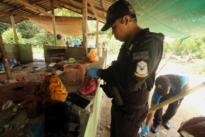 A Thai forensic expert and a military personnel examine the site where village defence volunteers were killed by suspected separatist insurgents in Yala province