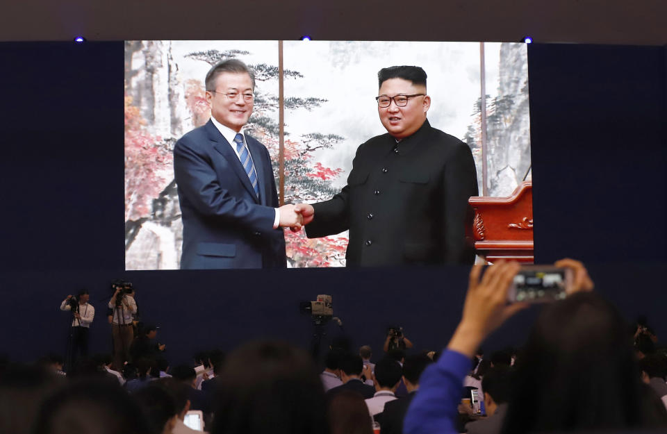 Members of media and volunteers watch a huge screen showing South Korean President Moon Jae-in, left, shake hands with North Korean leader Kim Jong Un after a joint press conference in Pyongyang (AP)