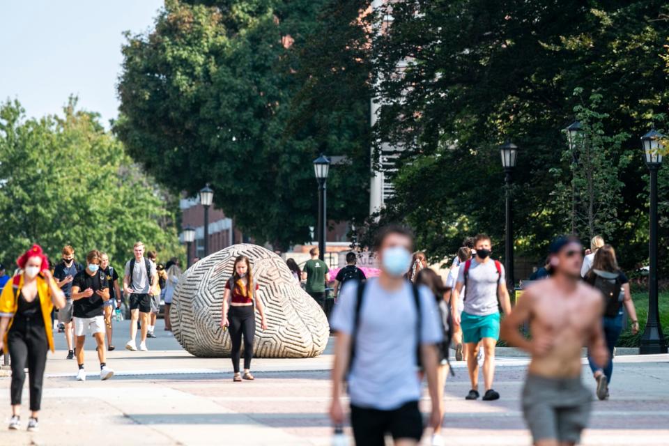 Students wearing face masks walk along the T. Anne Cleary Walkway on Aug. 24, the first day of in-person classes at the University of Iowa.