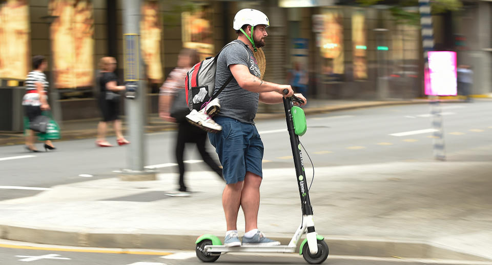 A Lime user crosses the street in a scooter around the Brisbane CBD