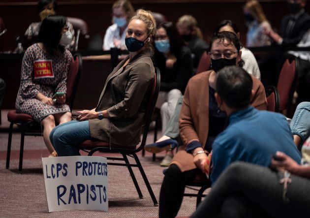 A woman sits with her sign during a LCPS board meeting in Ashburn on Oct. 12, 2021.