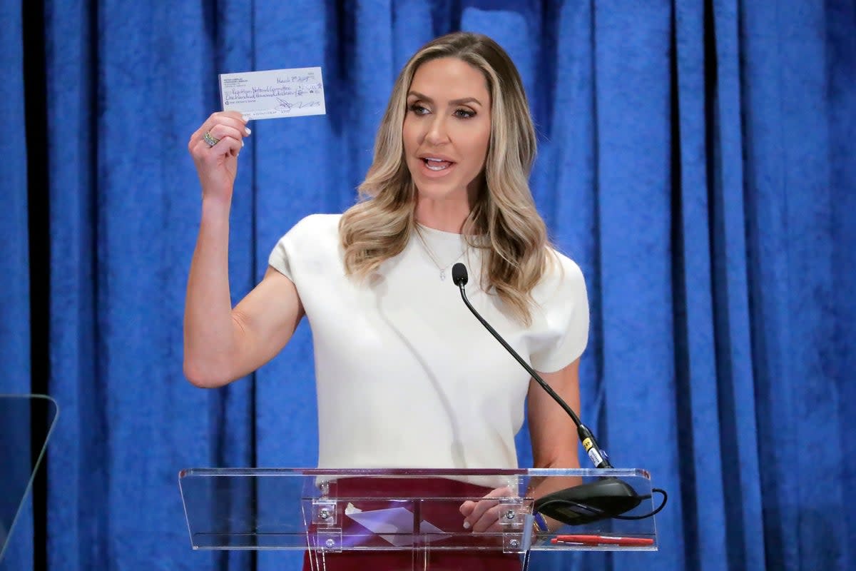 Lara Trump, the newly elected co-chair of the Republican National Committee, holds up a donation check as she gives an address during the general session of the RNC Spring Meeting on 8 March in Houston, Texas. (AP)