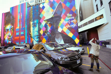 Mandy Fallen of St. Cloud photographs a mural of Bob Dylan, the 2016 Nobel Prize winner in literature, in Minneapolis, Minnesota, U.S., October 13, 2016. The mural was created by Brazilian artist Eduardo Kobra and his team. REUTERS/Craig Lassig