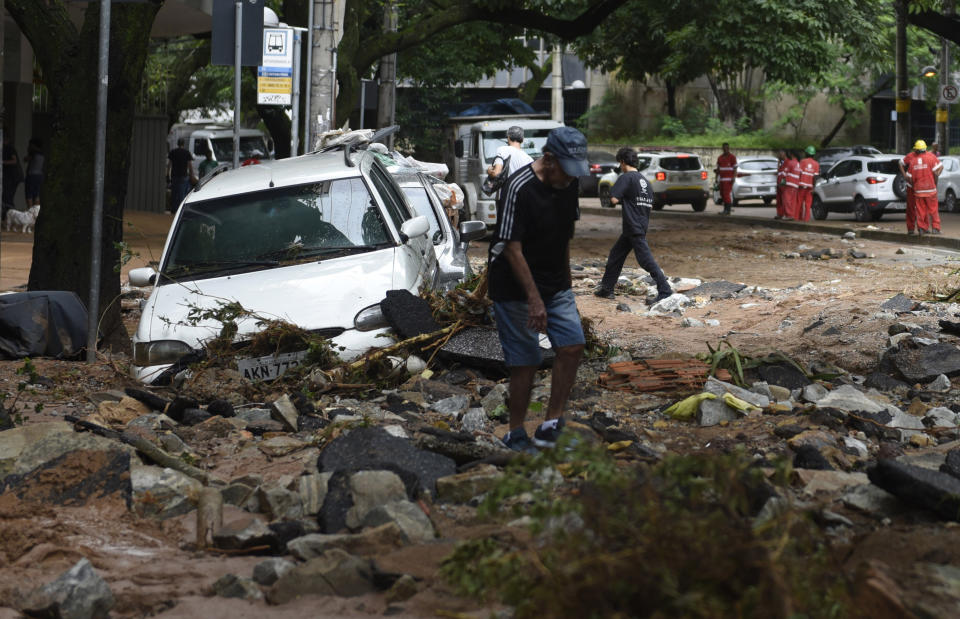 A man walks through the rubble of a street and cars destroyed by heavy rains in Belo Horizonte, Minas Gerais state, Brazil, Wednesday, Jan. 29, 2020. Heavy rains devastated the Brazilian state of Minas Gerais on Tuesday night and Wednesday morning, causing destructive flooding and landslides. (AP Photo/Gustavo Andrade)