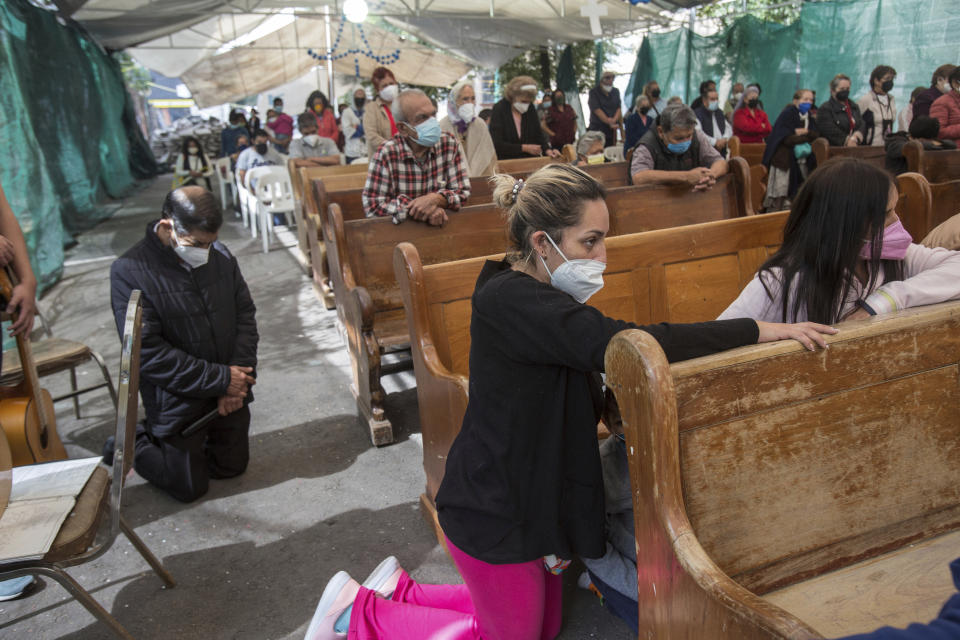 Devotees kneel in prayer during an outdoor Mass held under a tent just outside the quake-damaged Our Lady of the Angels Catholic church, in the Guerrero neighborhood of Mexico City, Sunday, Aug. 7, 2022. According to the National Institute of Anthropology and History, Our Lady of the Angels is the second most important temple in Mexico City after the internationally revered Basilica of Guadalupe. (AP Photo/Ginnette Riquelme)