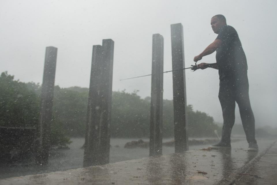 Jose Yartu, of Belle Glade, reels in his fishing line while being lashed by sheets of rain at Ocean Inlet Park near the Boynton Beach Inlet on  June 1, 2023.