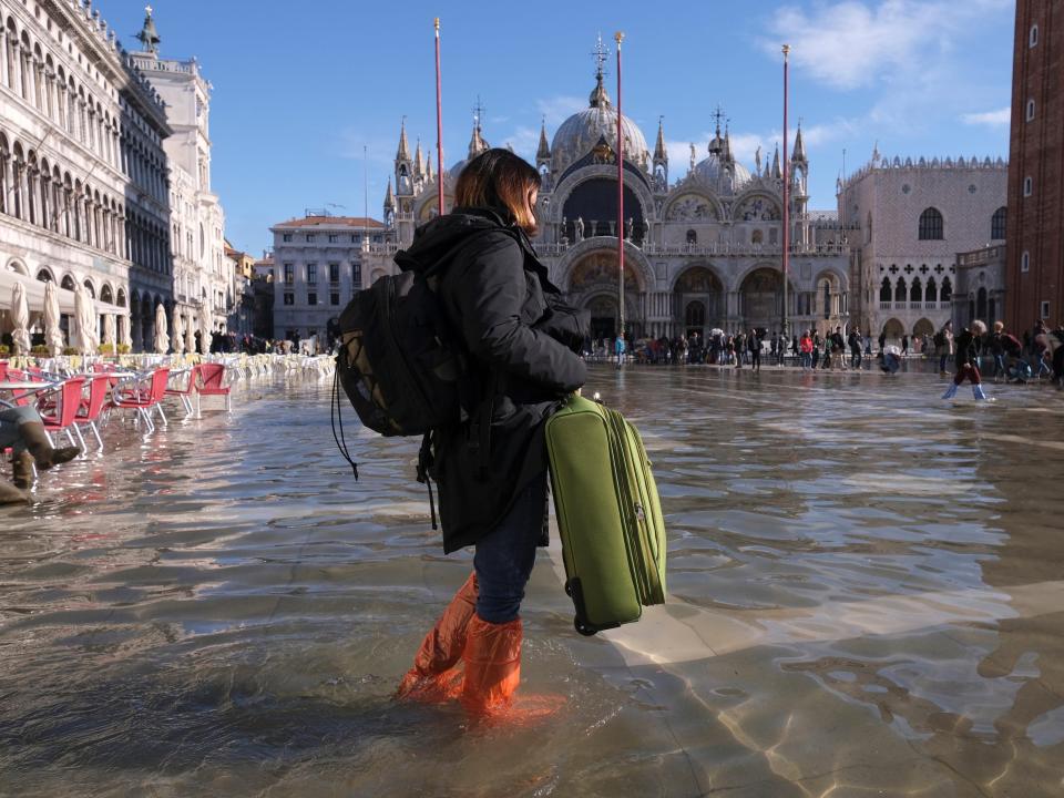 A woman carries a suitcase through a flooded St. Mark's Square during seasonally high water in Venice, Italy November 5, 2021.