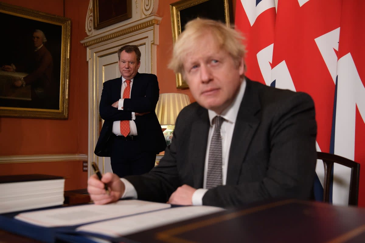 Boris Johnson signs the EU-UK Trade and Co-operation Agreement at 10 Downing Street as UK chief trade negotiator David Frost looks on (Leon Neal/PA)