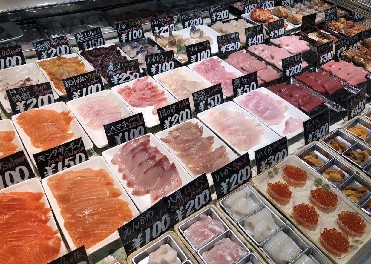 A variety of raw fish and seafood for sale in Japan with prices.