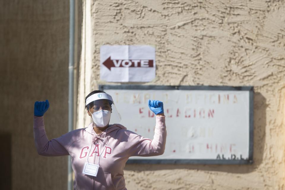 A poll worker celebrates as people drive to cast an early vote in the 2020 election at an early ballot location at the Betania Presbyterian Church in Phoenix on Oct. 28, 2020.
