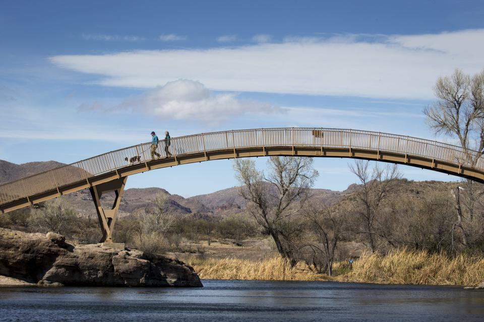 Steve Simpson (left), Roxanne Haidle (both Montana) and their dog, Jake, walk over the pedestrian bridge, February 12, 2018, at Patagonia Lake State Park, Arizona.