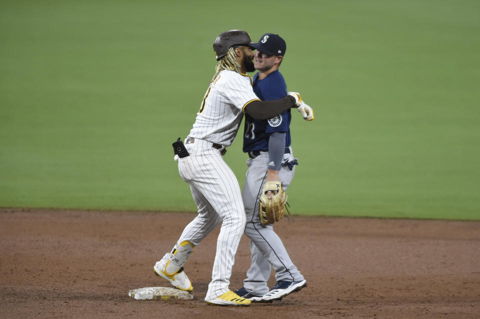 San Diego Padres' Fernando Tatis Jr. (23) hugs Seattle Mariners shortstop Dylan Moore (25) after hitting a double during the third inning of a baseball game Saturday, Sept. 19, 2020, in San Diego. (AP Photo/Denis Poroy)