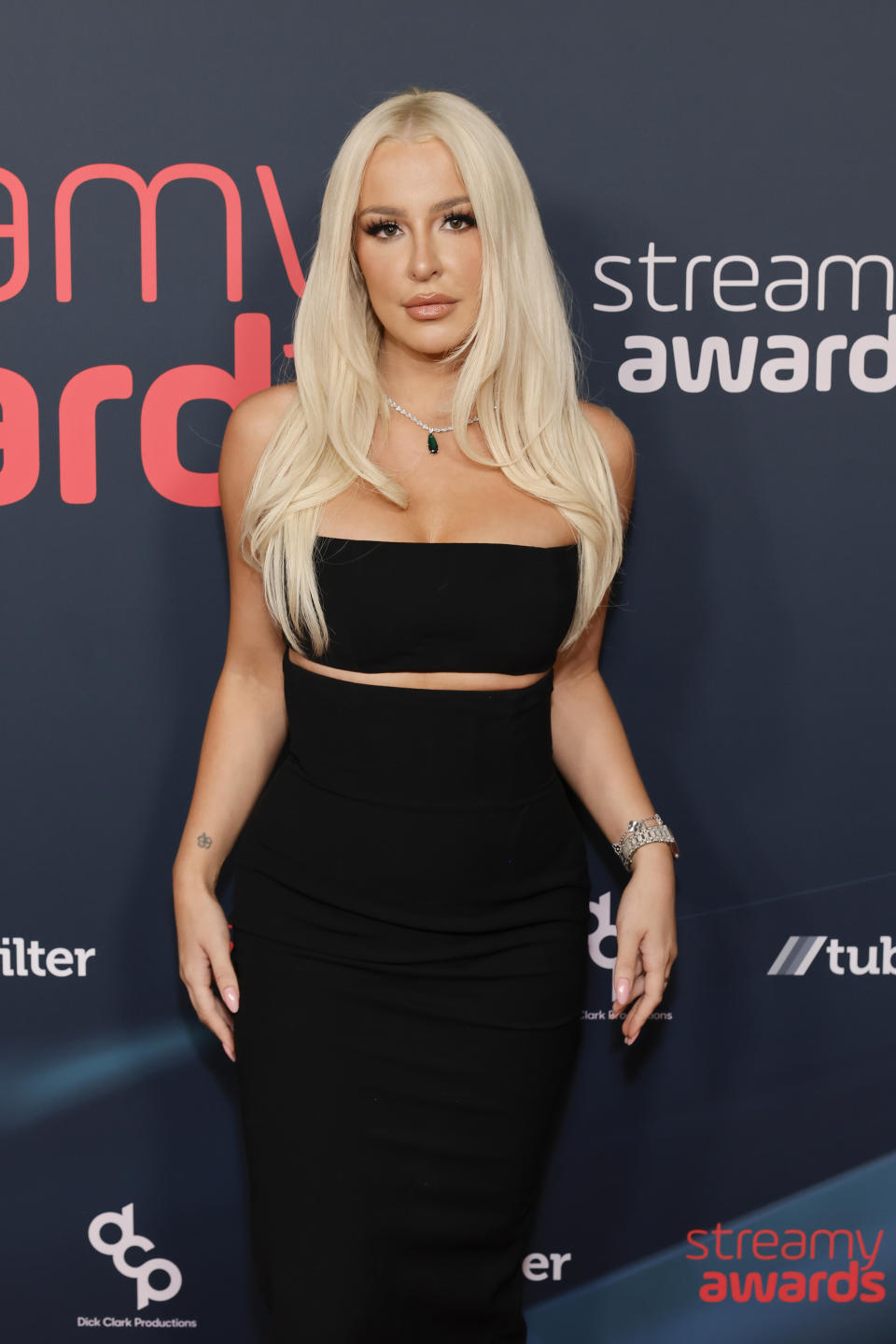 Tana Mongeau at the Steamy Awards, wearing a black two-piece outfit with a strapless top and a long skirt