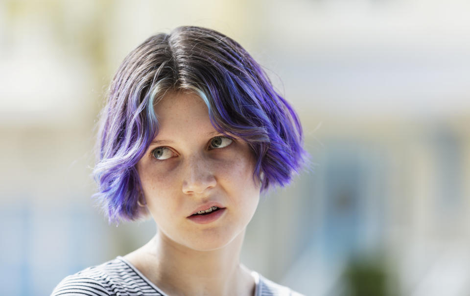 Person with short purple hair and light blue streaks looking off to the side, annoyed