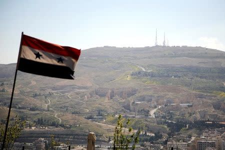 A Syrian national flag flutters as Qasioun mountain is seen in the background from Damascus, Syria. REUTERS/Omar Sanadiki