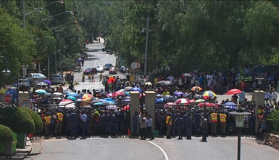 Still image from SABC video showing people standing behind the closed gates of the Union Buildings in Pretoria