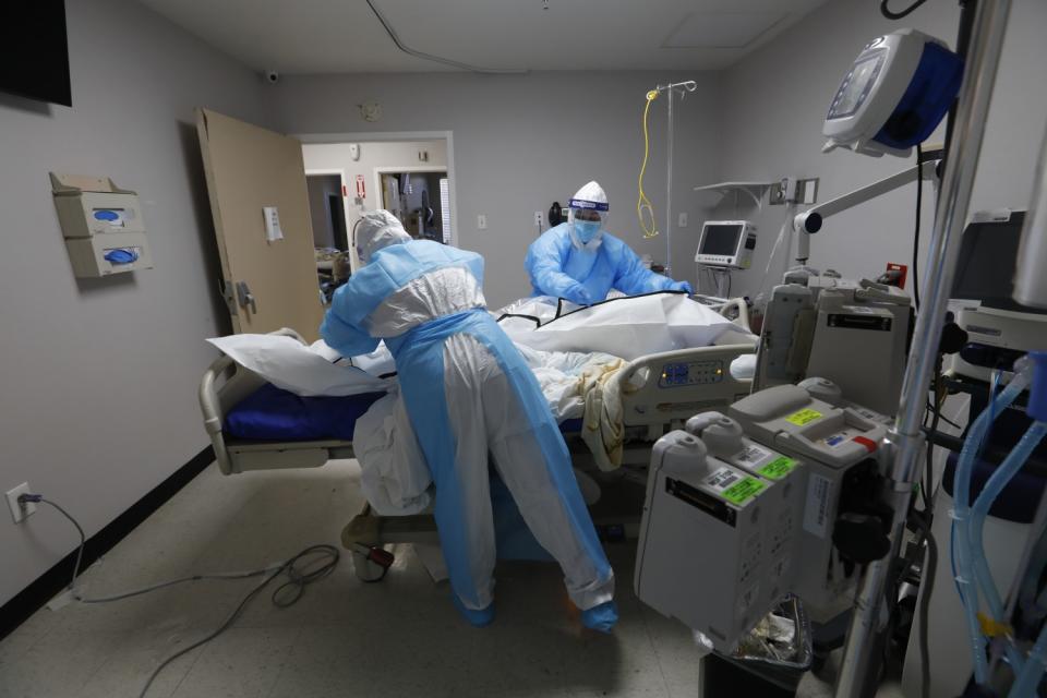 Flor Treviño, right, helps a fellow nurse clean and ease a former patient into a body bag