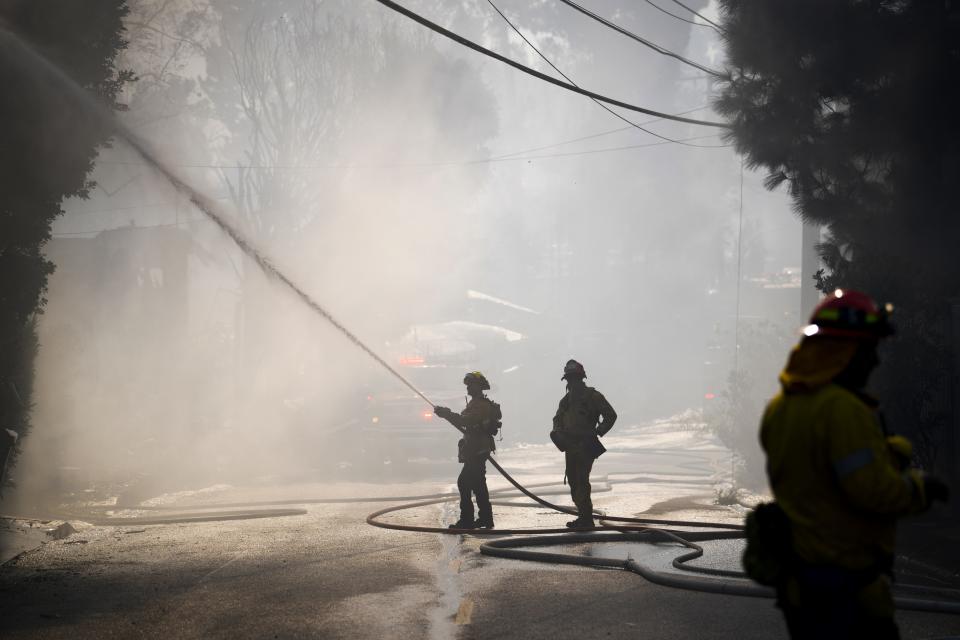 Los Angeles County Firefighters put out a house fire that was caused by the Getty Fire in the Brentwood Heights neighborhood of Los Angeles.