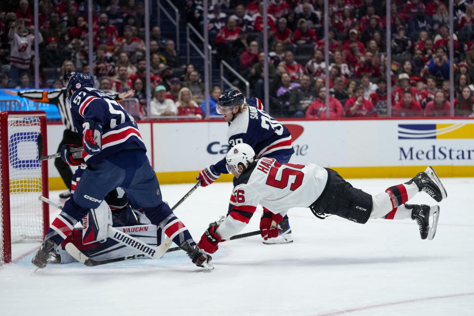 New Jersey Devils left wing Erik Haula (56) dives for the puck Washington Capitals defenseman Trevor van Riemsdyk, at left, in the second period of an NHL hockey game, Thursday, March 9, 2023, in Washington. (AP Photo/Alex Brandon)