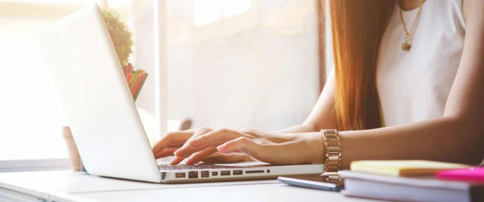 Close up of young woman using laptop in sunny room