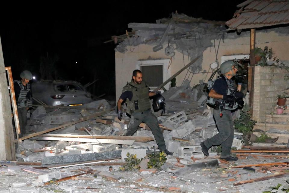 Three people in uniform navigate debris on the ground