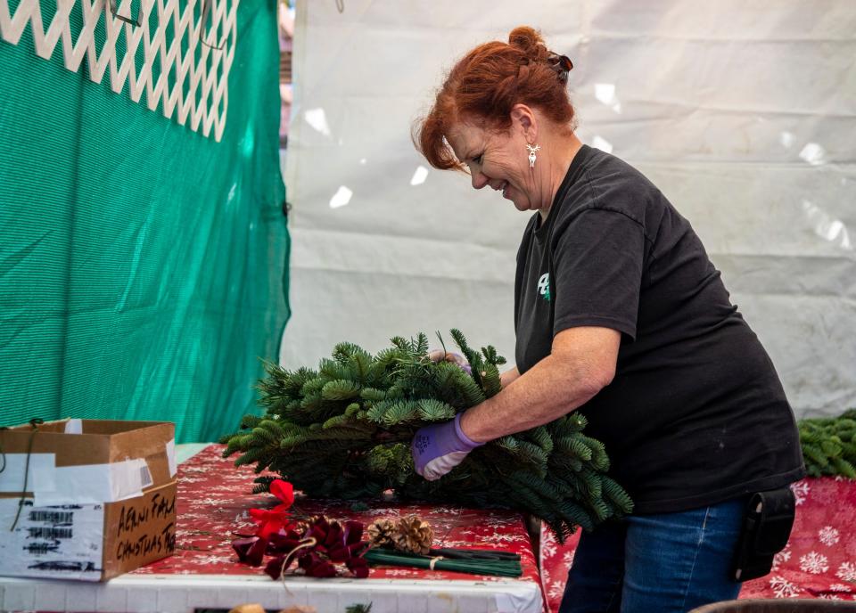 Rosie Aerni, a second-generation Christmas tree farmer, prepares a wreath at the Aerni Family Christmas Tree lot in Cathedral City in 2022. She spends all year at her home in Oregon making bows and tying pinecones and other decorations to go with her wreaths, then assembles them on site in Cathedral City when the family begins selling their trees.