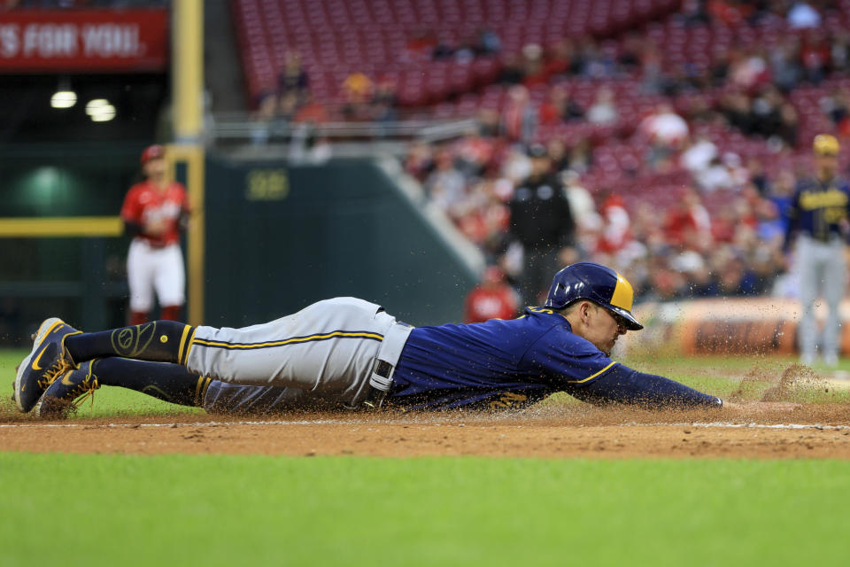 Milwaukee Brewers' Luis Urias slides into home plate as he scores a run on a throwing error by Cincinnati Reds' Aristides Aquino during the second inning of a baseball game in Cincinnati, Friday, Sept. 23, 2022. (AP Photo/Aaron Doster)