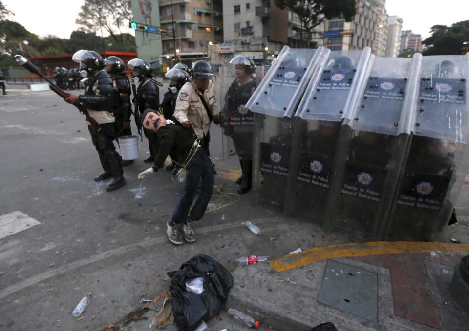 A Bolivarian National Police officer removes an effigy of Venezuela's President Nicolas Maduro during clashes with anti-government protesters in Caracas, Venezuela, Wednesday, March 5, 2014. The one year anniversary of the death of Venezuela's former President Hugo Chavez was marked with a mix of street protests and solemn commemorations that reflected deep divisions over the Venezuela he left behind. (AP Photo/Fernando Llano)